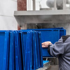 Professionnels en action lors du nettoyage et de la désinfection des bacs EURO dans un tunnel de lavage respectant les normes d'hygiène et de sécurité alimentaire